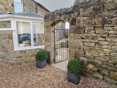 A garden with a stone wall and a gate at Linn Cottage in Hexham