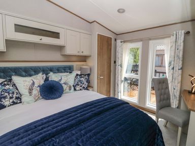 A bedroom with a bed and windows at The Beaumont No 34 in New Quay