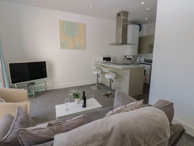 A living room with a television and kitchen area at Harbour View in Whitehaven