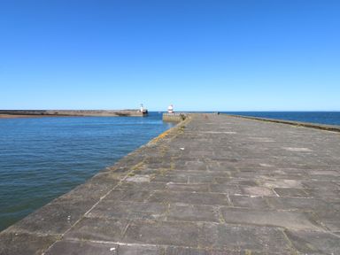 A pier extending into water with lighthouses at Harbour View in Whitehaven