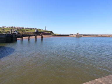 A coastal view with a pier and houses at Harbour View in Whitehaven