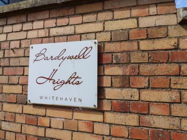 A sign for Bardywell Heights on a brick wall in Whitehaven