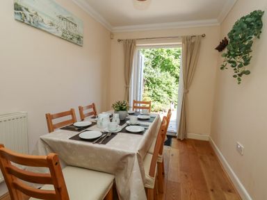 A dining room with a table set for meals at Fairways House in Weymouth