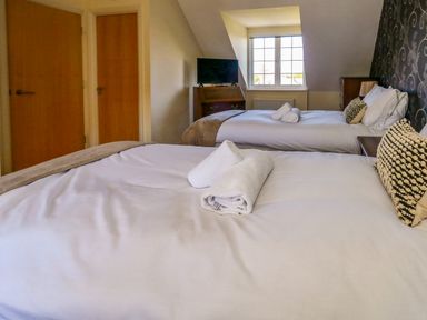 A bedroom with two beds and a television at Fairways House in Weymouth