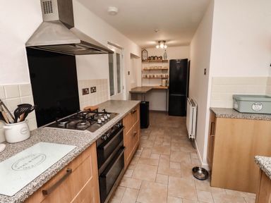 A kitchen with stove, refrigerator and shelves at Bari House in Seahouses