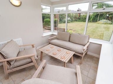 A conservatory with seating and a view of the garden at Bari House in Seahouses