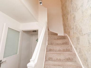 A staircase with carpet and wall design at Bari House in Seahouses