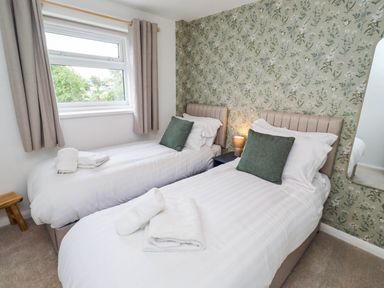 A bedroom with two beds and a window at Bari House in Seahouses