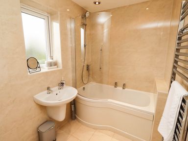 A bathroom with a bathtub and sink at Bari House in Seahouses
