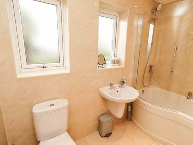 A bathroom with a sink, shower, bath, and toilet at Bari House in Seahouses