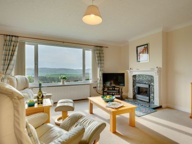 A living room with an armchair, coffee table, and fireplace at The Granary in Alnwick