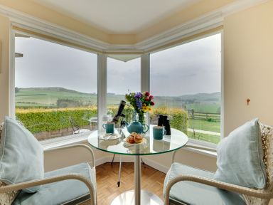 A dining area with a table, chairs, and view at The Granary in Alnwick