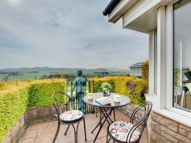 An outdoor seating area with a table and chairs overlooking a landscape at The Granary in Alnwick