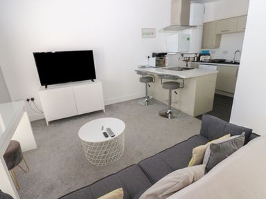 A living room with a television and kitchen island at Harbourside Apartments Whitehaven