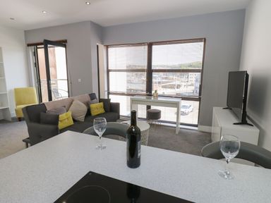 A living room with a sofa and a television at Harbourside Apartments in Whitehaven