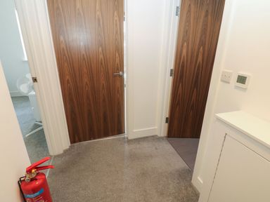 A hallway with a fire extinguisher and two doors at Harbourside Apartments in Whitehaven