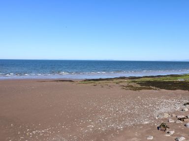 A beach with sand, sea, and rocks at Harbourside Apartments in Whitehaven