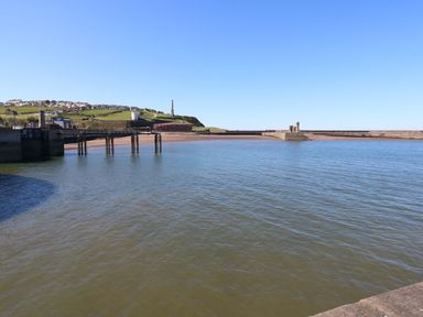 A view of a pier over water with hills in the background at Harbourside Apartments Whitehaven