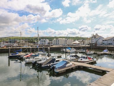 A marina with boats docked and buildings in the background at Harbourside Apartments Whitehaven