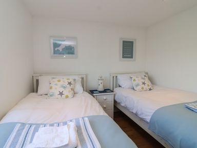 A bedroom with two single beds and a nightstand at Stella Maris in Torpoint