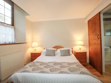A bedroom with a bed and bedside tables at The Stables in Falmouth