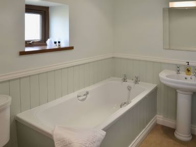 A bathroom with a bath tub, sink, and toilet at The Stables Budock Water near Falmouth