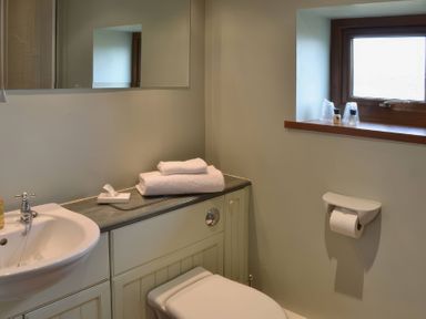 A bathroom with a sink, toilet, and towels at The Stables Budock Water near Falmouth