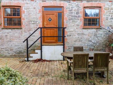 An outdoor area with a wooden table and chairs at Horseshoe Cottage in Falmouth