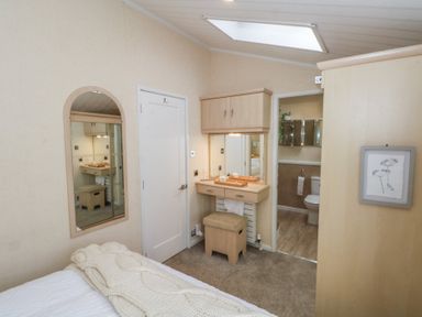 A bedroom with a dressing table and bathroom access at Labernum in Lytham St. Annes