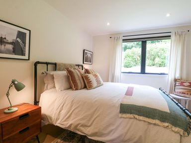 A bedroom with a bed and bedside table at Lakeside Lodge near Burwash