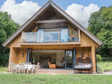 A wooden house with a deck and outdoor furniture at Lakeside Lodge Witherenden Hill near Burwash