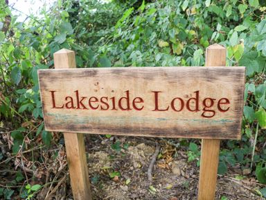 A wooden sign reading Lakeside Lodge surrounded by greenery