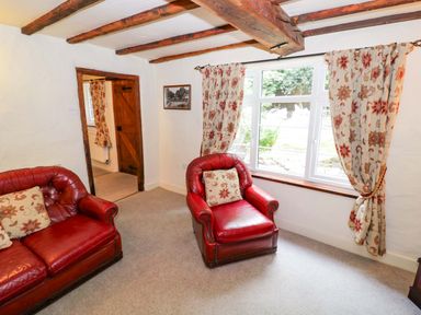 A living room with two red armchairs and a window at Fern Cottage in 