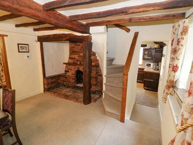 A living room with a fireplace and staircase at Fern Cottage