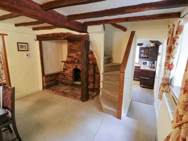 A living room with a fireplace and stairs at Fern Cottage