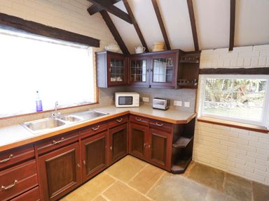 A kitchen with cabinets, sink, and appliances at Fern Cottage