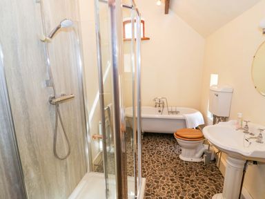 A bathroom with shower, bathtub, toilet, and sink at Fern Cottage in 