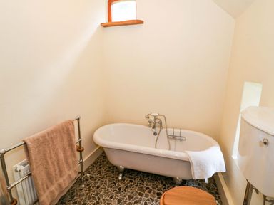 A bathroom with a bathtub and towel rack at Fern Cottage in 