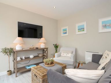 A living room with a television and seating area at Evelyn in Looe