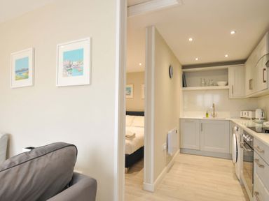 A living room with a kitchen and bed visible at Evelyn in Looe