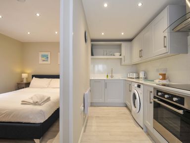 A kitchen with a bed and nightstand at Evelyn in Looe