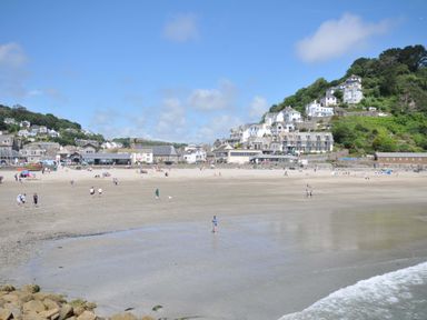 A beach with people and houses in the background at Evelyn in Looe