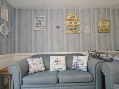 A living room with a blue sofa and decorative pillows at 13 Hillside in Bude
