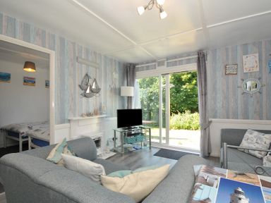 A living room with a television and sliding door at 13 Hillside in Bude