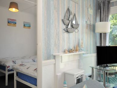 A living room with a bed and decorative items at 13 Hillside in Bude