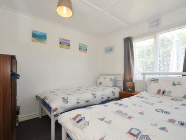 A bedroom with two beds and a wardrobe at 13 Hillside in Bude