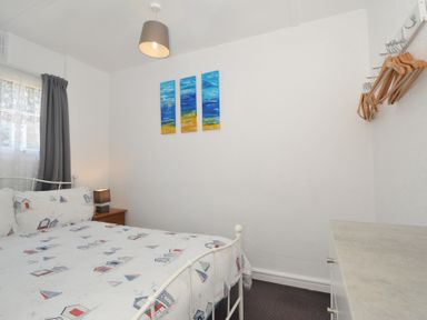 A bedroom with a bed and paintings on the wall at 13 Hillside in Bude