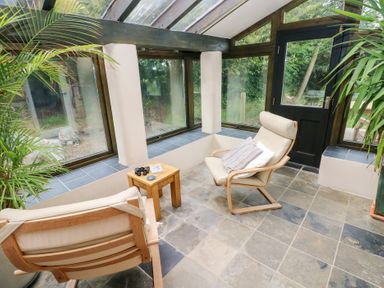 A conservatory with two chairs and a table at The Dovecote in Llanychaer near Fishguard