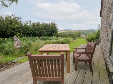 A table and chairs on a wooden deck overlooking greenery at The Dovecote near Fishguard