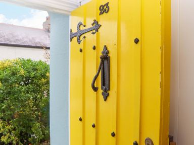 A yellow door with a handle and number 25 at Captains Cottage in Brixham